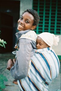 Young african mother with baby in kanga style carrier